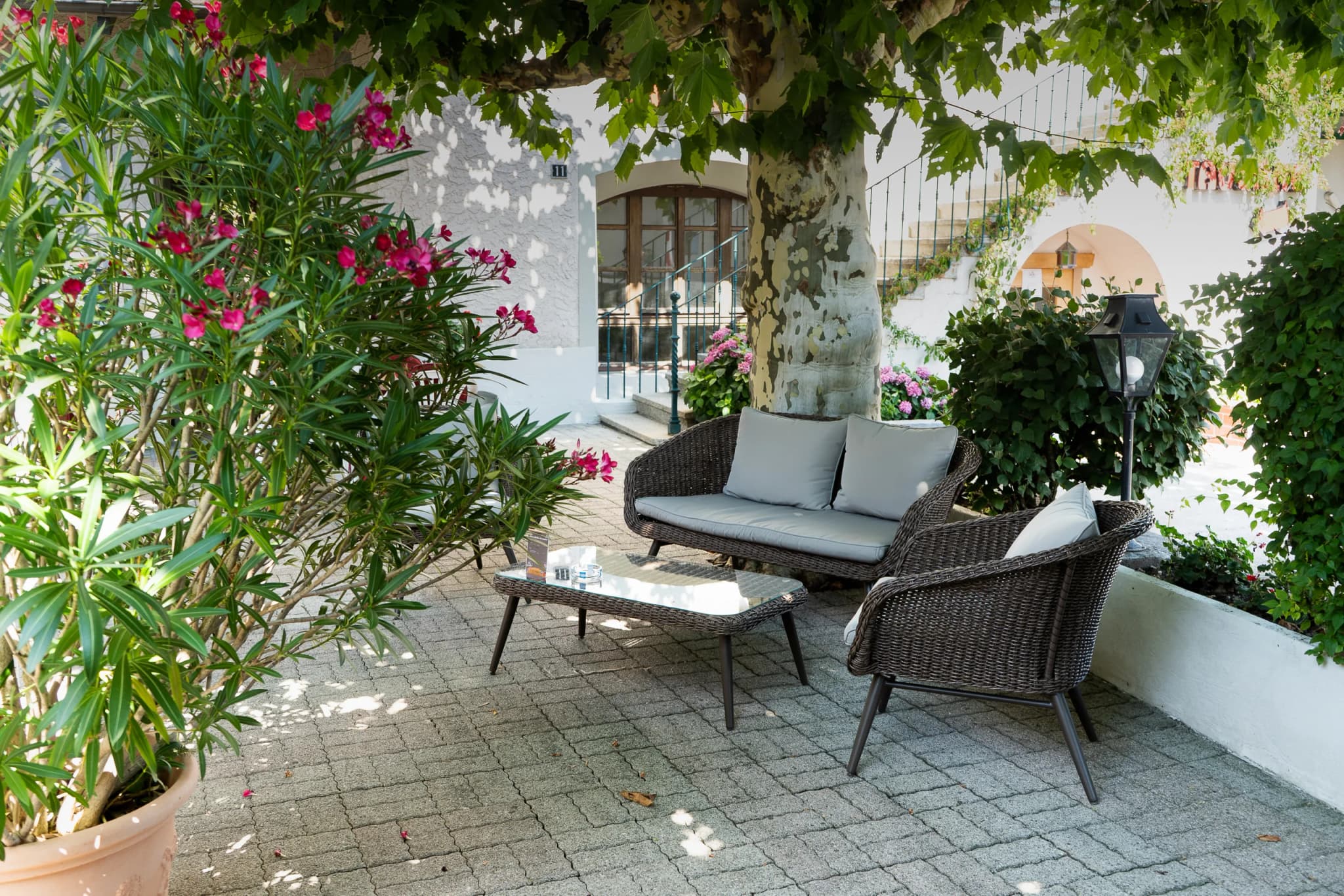 Salotto da giardino in rattan all’ombra di un platano, sulla terrazza dell’Hôtel de Bahyse